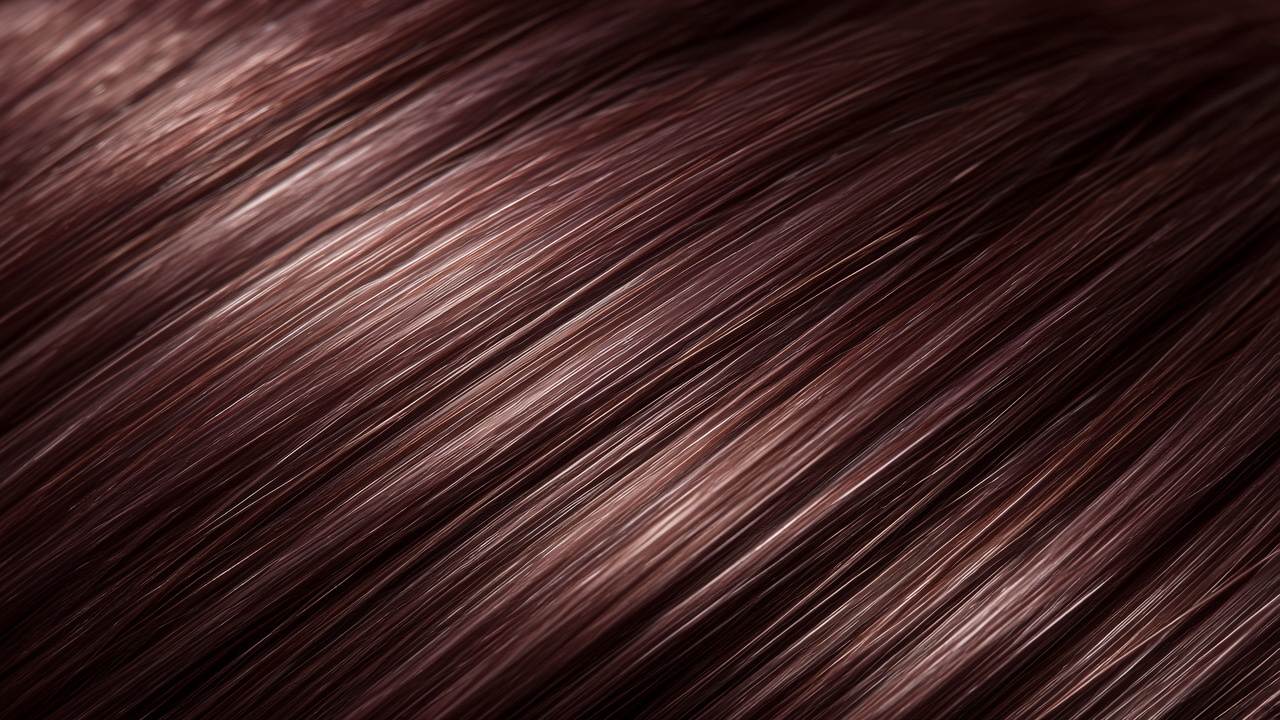 Glossy dark hair texture with soft mauve highlights in editorial light